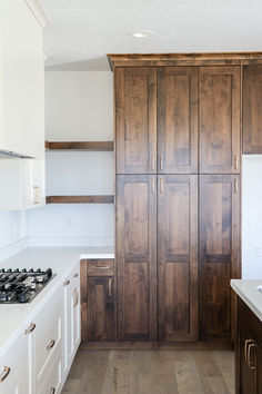 an empty kitchen with wooden cabinets and white counter tops, along with wood flooring