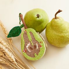 two pears, one green and one brown with beaded designs on the side