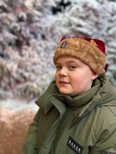 a young boy wearing a fur hat and green jacket