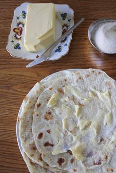 three tortillas are on a plate with butter and spoons next to them