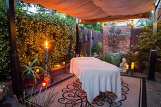 a spa room with a table covered by a white sheet and lit candles in the corner