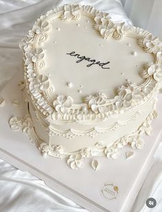 a heart - shaped cake with the word happy written on it sits on a white tablecloth