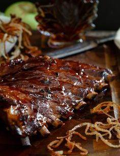 ribs and onion rings on a cutting board with an apple in the backgroud