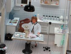 a doll is sitting at a table in a room with many objects on the floor