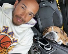 a man sitting in the back seat of a car next to a dog on his lap