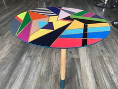 a multicolored table with wooden legs on wood flooring in a living room