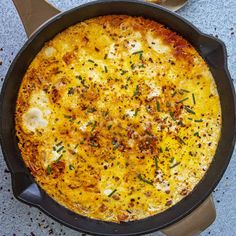 an omelet with cheese and herbs in a cast iron skillet on a table