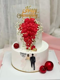 a white and red wedding cake with hearts on the top, surrounded by christmas ornaments