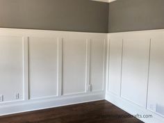 an empty room with white paneling and wood floors