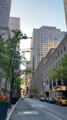 an empty city street with tall buildings in the back ground and cars parked on the side