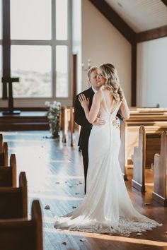 a bride and groom standing in front of pews