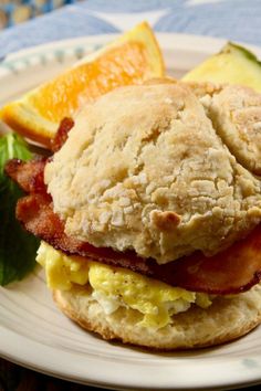 a breakfast sandwich on a plate with orange slices