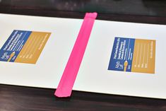 a pink toothbrush sitting on top of a white paper next to an open book