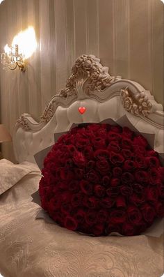 a large bouquet of red roses sitting on top of a bed