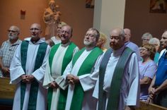 group of men in green and white robes standing next to each other at a church