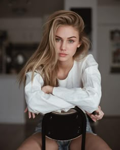 a woman sitting on top of a chair with her arms crossed