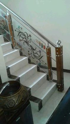 a stair case next to a railing with decorative designs on the glass and wood handrails