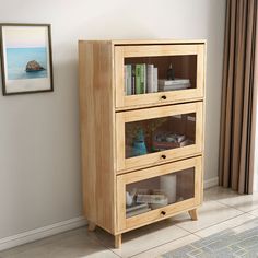 a wooden cabinet with three drawers in front of a window and a painting on the wall