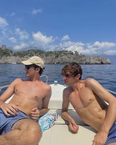 two young men sitting on the back of a boat