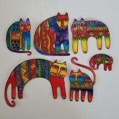 four colorful cats and two smaller ones on a white surface, each painted with different colors