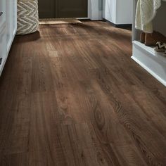 a hallway with wood flooring and white trim on the walls, along with an open door