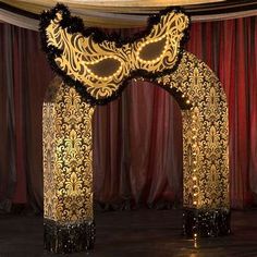 an elaborately decorated archway in the middle of a stage with red curtains behind it