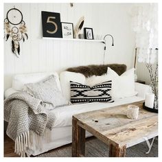 a living room filled with furniture and pillows on top of a white couch next to a wooden table