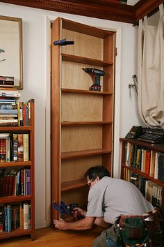 a man kneeling down in front of a book shelf