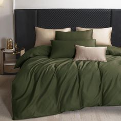 a bed with green sheets and pillows in a room