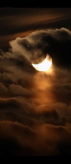 the moon is seen through clouds in this dark sky with orange and yellow light coming from it