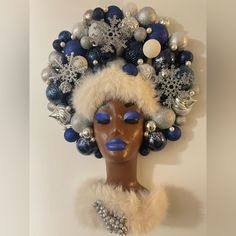 a mannequin with blue and silver decorations on it's head, in front of a white wall