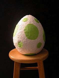 a paper mache sitting on top of a wooden stool with green polka dot designs