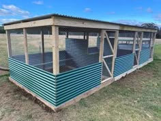 a chicken coop in the middle of a field with grass and blue sky behind it