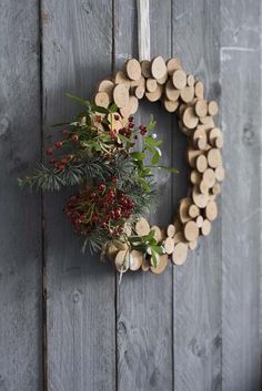 a wreath hanging on the side of a wooden wall with branches and berries around it