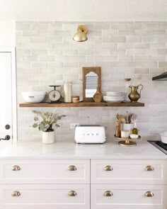 a kitchen with white cabinets and gold knobs on the shelves above the countertop