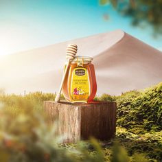 a jar of honey sitting on top of a wooden post