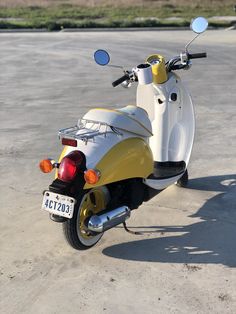 a yellow and white scooter parked in an empty parking lot with no one on it