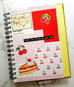 an open notebook with pictures and words on it, including cherries in the background