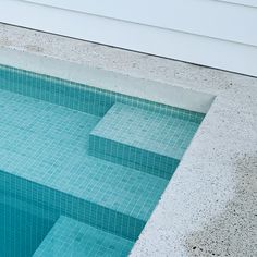 an empty swimming pool with steps leading up to the edge and blue tiles on the floor