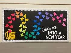 a bulletin board with colorful origami birds and the words soaring into a new year