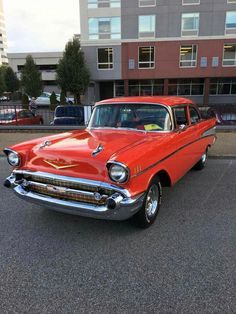 an old red car parked in a parking lot