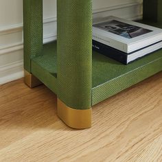 a book is sitting on top of a green chair next to a white wall and wooden floor