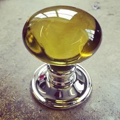 a close up of a glass door knob on a metal object with a yellow liquid in it