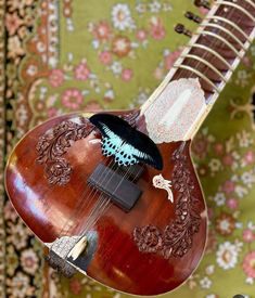 a close up of a guitar with a butterfly on it's back and neck