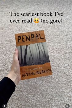 a person holding up a book in front of a white carpet with the title penpal written on it