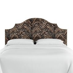 an upholstered bed with white sheets and zebra print headboard on top of it