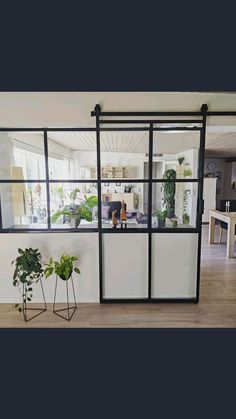 a living room filled with furniture next to a window covered in plants and potted plants