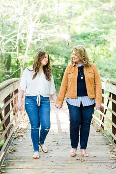 two women walking across a bridge holding hands