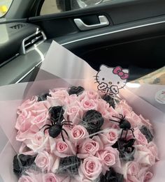 a bouquet of pink roses and black spideres in a paper wrapper on the dashboard of a car