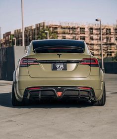 the rear end of a beige car parked in a parking lot